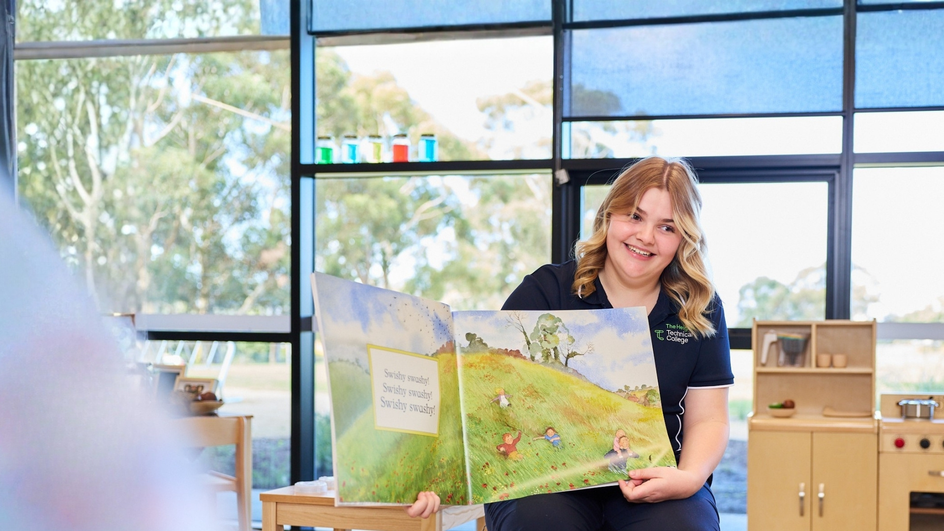 Early childhood education student reading a picture book in a childcare learning space.
