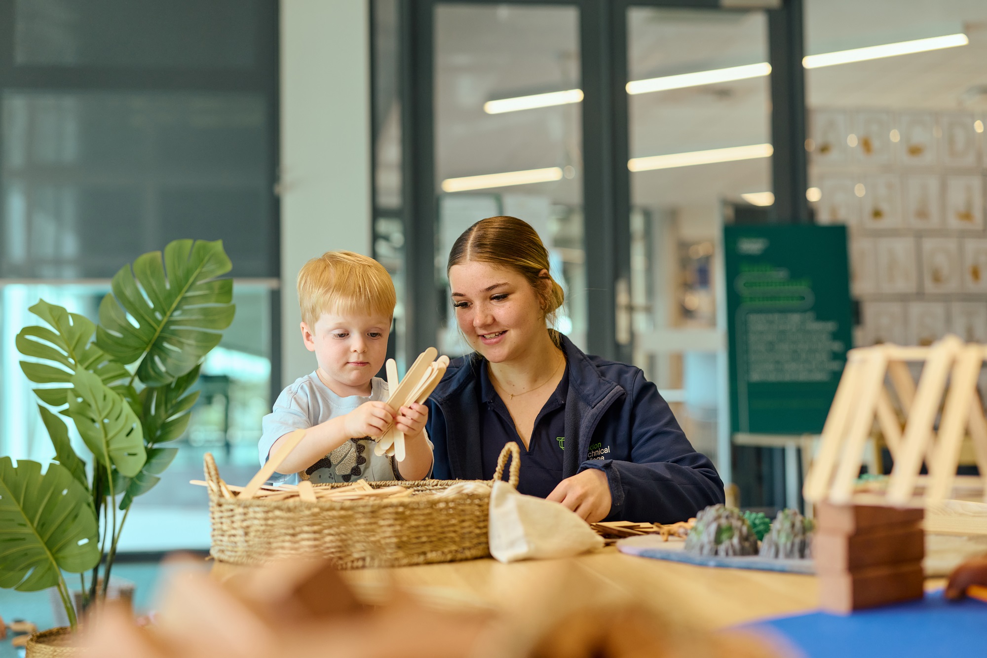Student with young child in an early learning classroom setting.