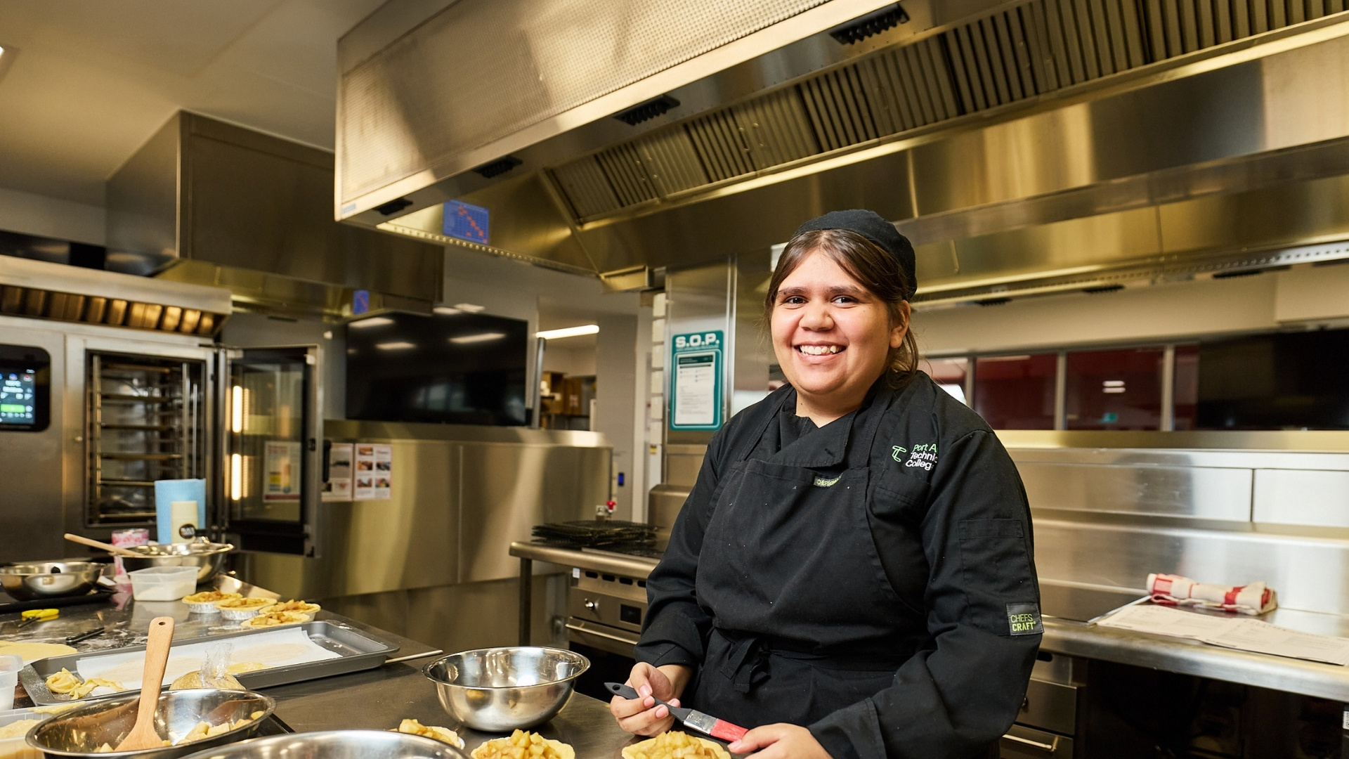 Cookery student preparing pastries in a commercial training kitchen.