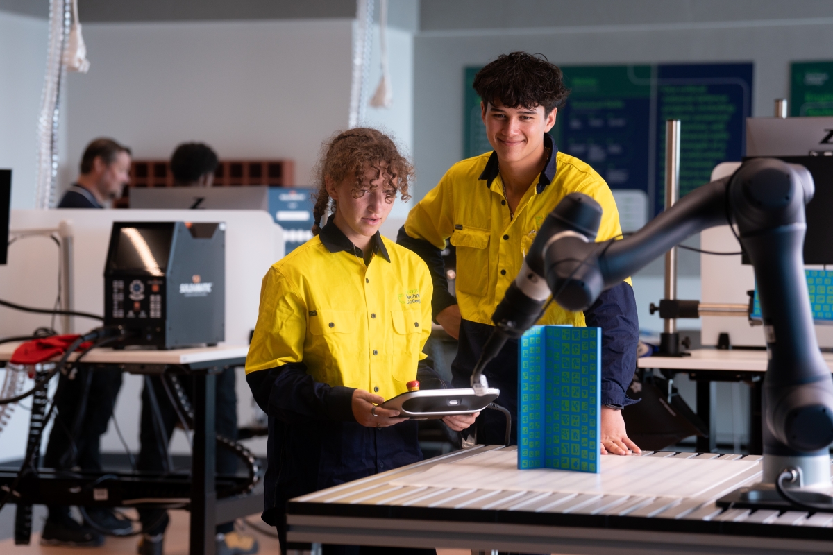 Two students in uniform in a robotics lab. 